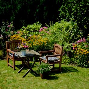 Stühle und Tisch im schönen Garten mit Blumen