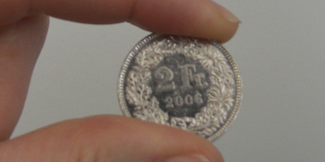 Frankenmünze wird zwischen zwei Fingern gehalten